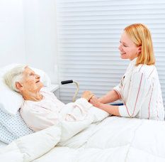 senior woman and beautiful caregiver smiling at each other