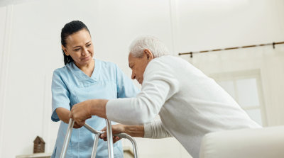 caregiver helping senior man to stand up